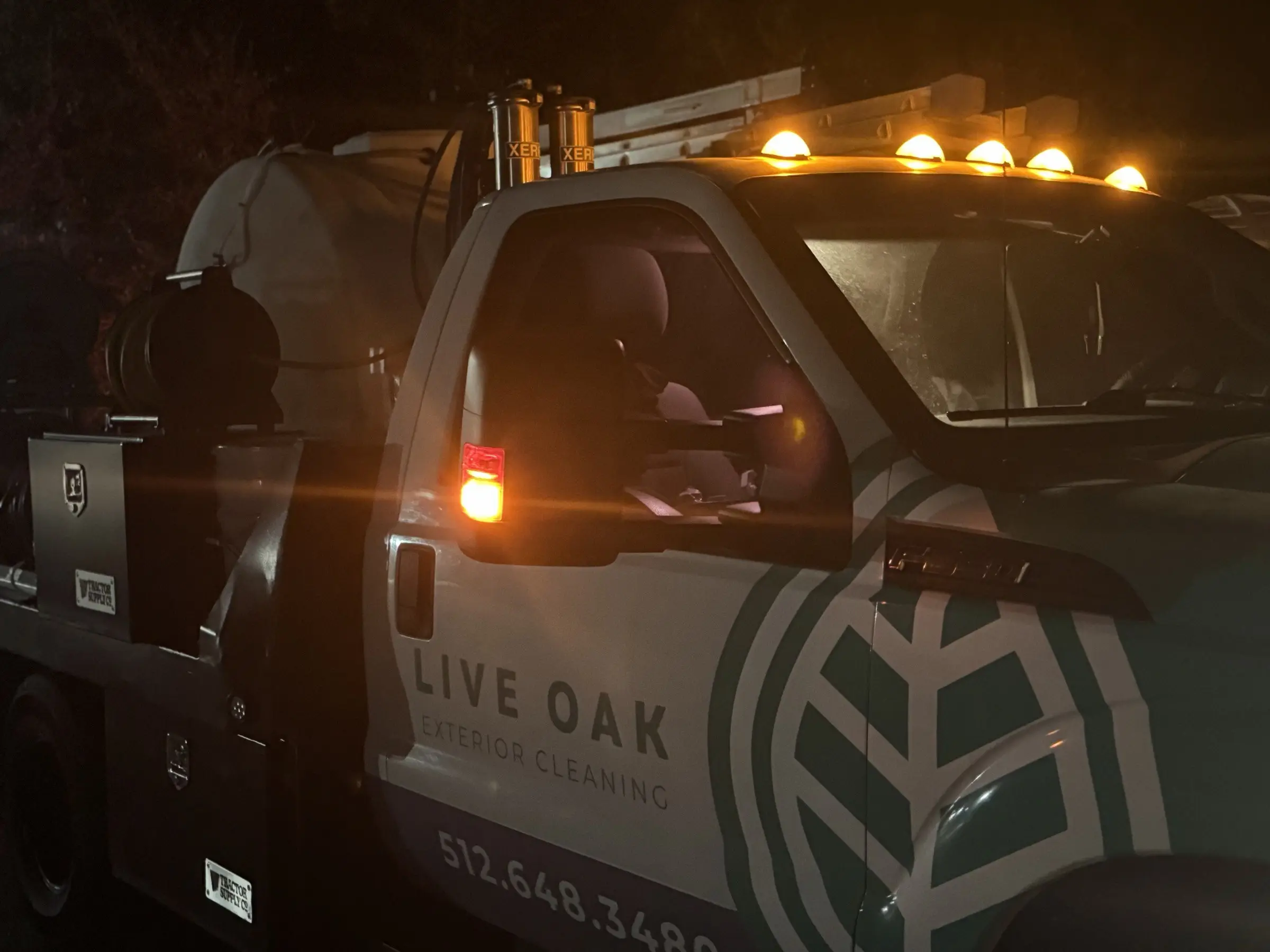 The Live Oak truck parked on the shopping center lot before dawn with its amber beacons lit, tank and hose reels mounted in the bed