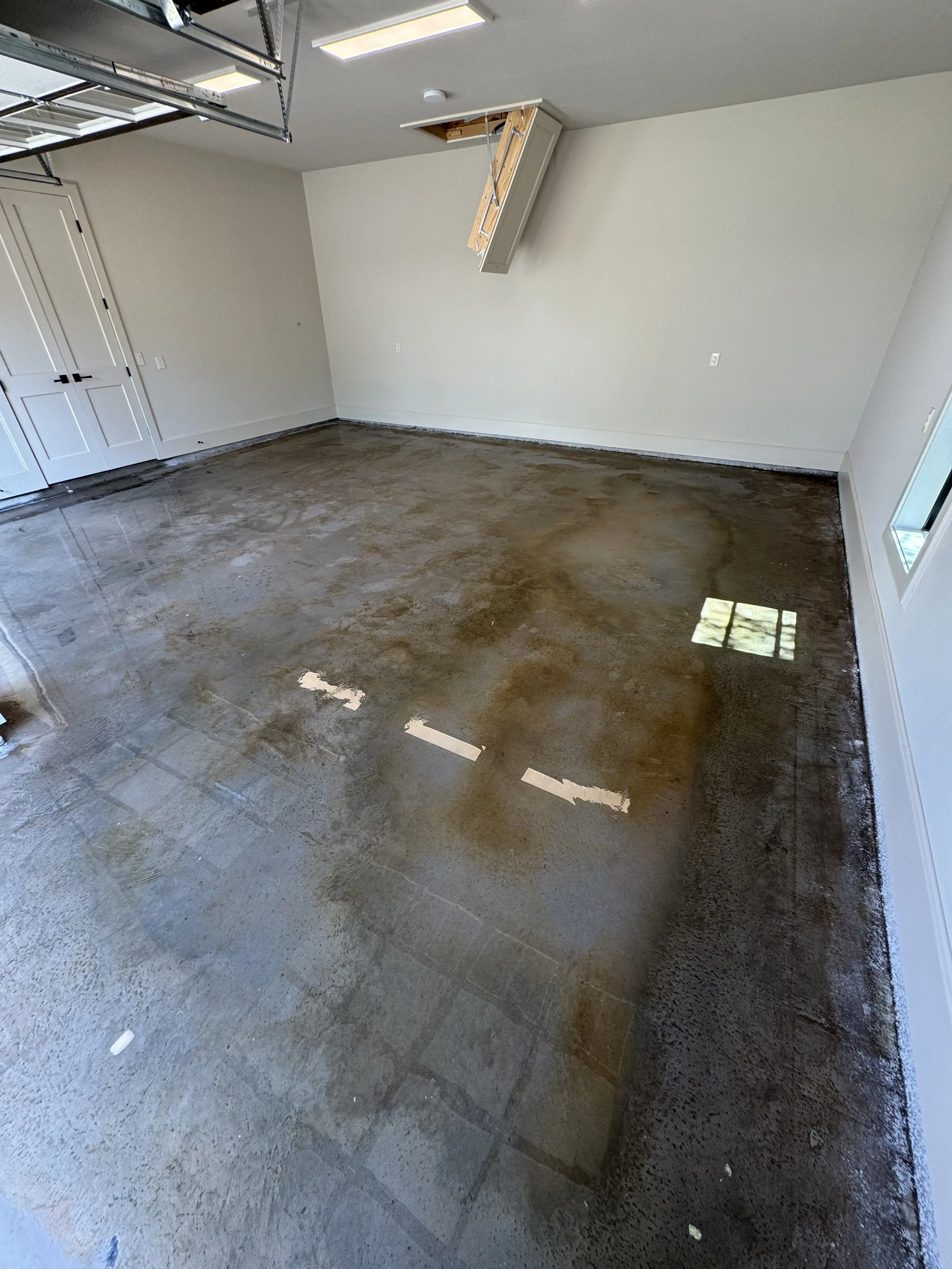 The same garage floor immediately after pressure washing, the slab wet and dark with the drywall splatter gone