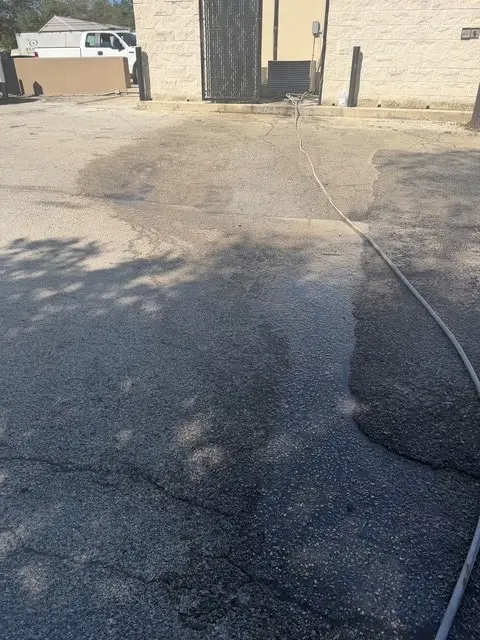 The hose run out across the wet asphalt behind the restaurant, the building's stone wall and a white truck parked beyond it