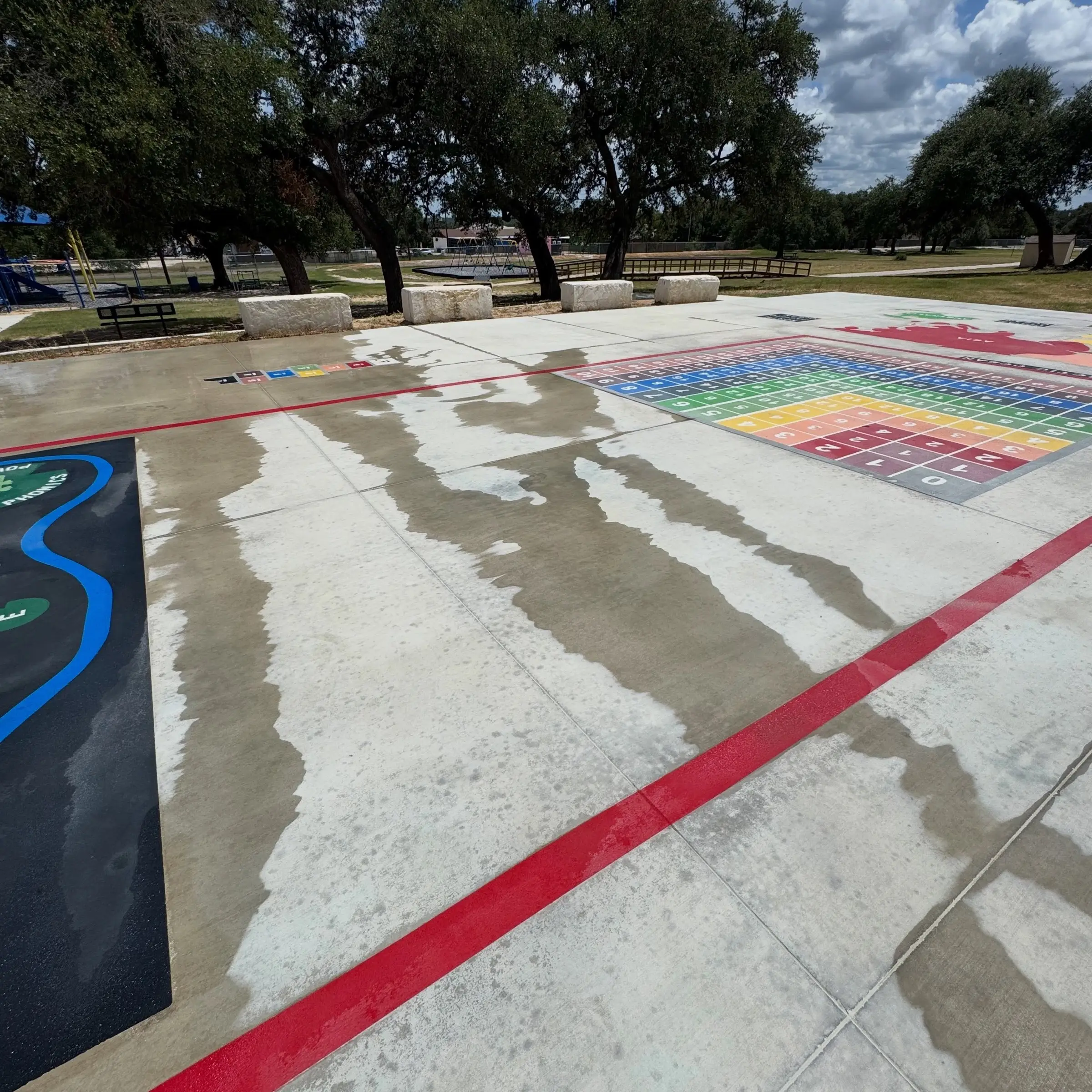 The same Blanco ISD learning surface part way through cleaning, bright cleaned passes running beside the untouched concrete