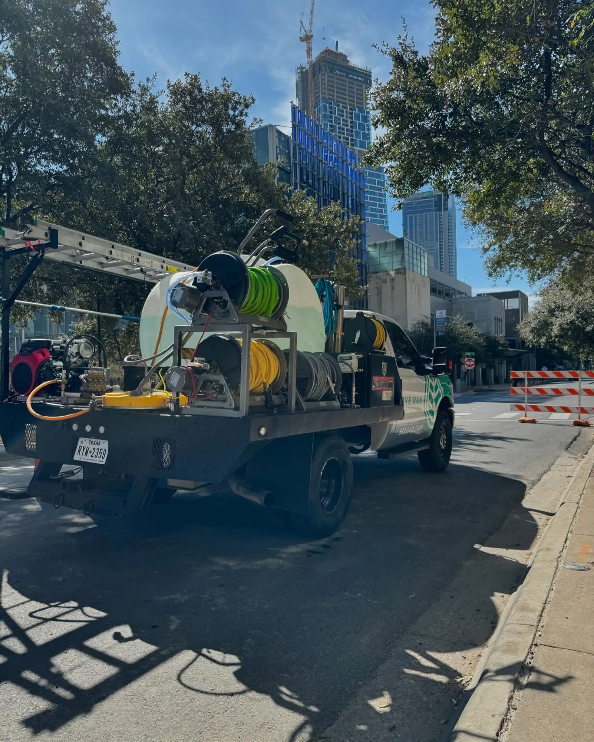 The Live Oak flatbed truck today, with a water tank, hose reels and ladders mounted in the bed, parked on a downtown Austin street